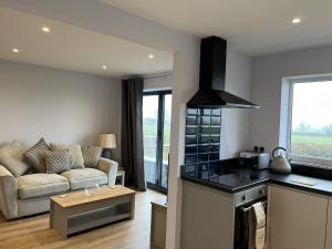 a kitchen and living room with a couch and a table at Genesis 1 bed cottage in Tunstall