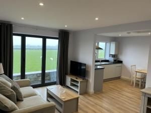 a living room with a couch and a tv and a kitchen at Genesis 1 bed cottage in Tunstall
