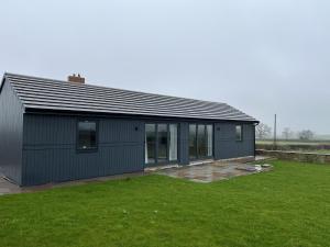 a gray house with a large grass yard at Genesis 1 bed cottage in Tunstall +4 photos