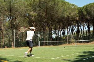 a man swinging a tennis racket on a tennis court at Cala dei Pirati in Punta Ala