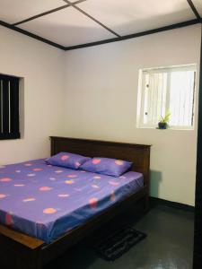een slaapkamer met een bed met paarse lakens en een raam bij Bambo Cabana in Kandy