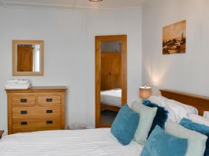 a bedroom with a bed with blue pillows and a mirror at Hillside in Praa Sands