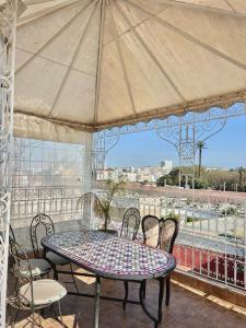 a table with chairs and an umbrella on a balcony at Riad Najiba in Rabat
