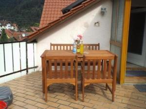 uma mesa de madeira e 2 cadeiras num pátio em Ferienwohnung Kirchblick - b51898 em Langenbrand