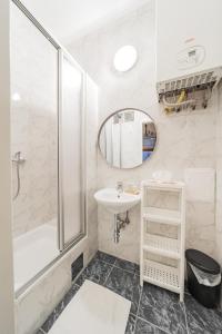 uma casa de banho branca com um lavatório e um chuveiro em Cosy Central Studio em Viena