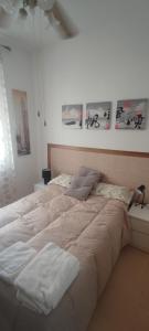 een groot bed in een witte kamer met foto's aan de muur bij Apartamento en el corazon de Triana in Sevilla