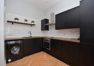 a kitchen with black cabinets and a washing machine at 2 BDR apartment at QUEENS UNI by Belfast City Breaks in Belfast