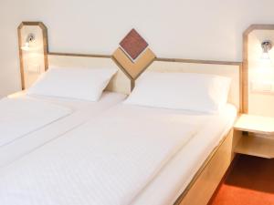 2 letti in una camera con lenzuola bianche di Hotel Burgklause a Nickenich