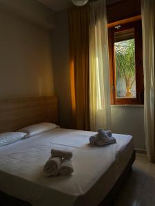 2 Handtücher auf einem Bett in einem Schlafzimmer mit Fenster in der Unterkunft Palazzo Durante in Letojanni