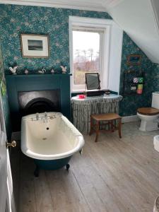 a bathroom with a bath tub and a table with a laptop at Glenaros Lodge in Salen