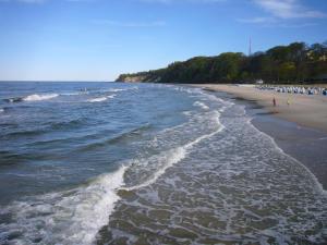 巴貝的住宿－Familie-und-Meer-2-Badezimmer-3-Schlafzimmer-Strandnah-im-Ostseebad-Baabe-Baabe，沙滩上的人在沙滩上和水里散步