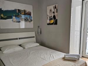 リスボンにあるWindow to Lisboa Iの白いベッドと壁にポスターが備わるベッドルーム1室