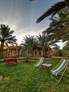 two lawn chairs and a table in a yard at Oasis Tilogui in Zagora