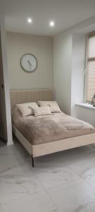 Un dormitorio con una cama con un reloj en la pared. en APARTAMENT JEDLINKA B, en Jedlina-Zdrój