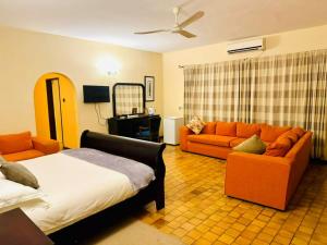 een woonkamer met een bed en twee oranje banken bij The White House of Victoria Falls in Victoria Falls