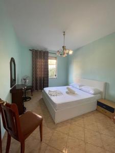 Guesthouse NEO في تيرانا: غرفة نوم بسرير ابيض كبير وكرسي