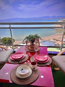 een tafel met roze borden en bekers en uitzicht op het strand bij Blue Salou in Salou