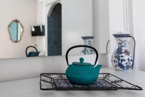 a green tea pot sitting on a table with vases at Olympia Hotel in Genoa