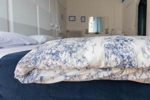 a bed with a blue and white blanket on it at Olympia Hotel in Genoa