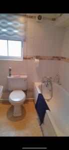 a bathroom with a toilet and a bath tub at Cwtch By The Sea in Porthcawl