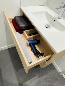 a drawer under a bathroom sink with a tool at Le Grand HELDER in Vichy +59 photos