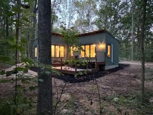 a tiny house in the woods with the lights on at Brand New Modern Cottage Hocking Hills in Stella