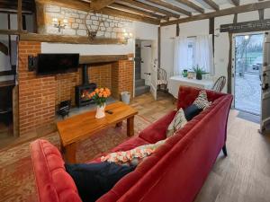 uma sala de estar com dois sofás vermelhos e uma lareira em The Cottage At Harple Farm em Detling