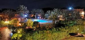 - une vue sur la piscine la nuit dans l'établissement Oasis Tilogui, à Zagora