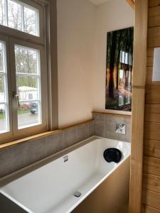 a large white bath tub in a room with two windows at Ferienwohnung am Stockerbach in Freudenstadt