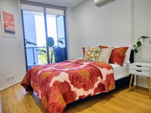 1 dormitorio con cama con edredón y ventana en Resort style 1 or 2 bedroom with pool and free parking en Hornsby