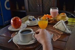 uma pessoa segurando uma xícara de café e uma xícara de suco de laranja em Portal del Sol em San Ignacio