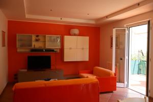 an orange living room with a couch and a tv at Giulio's terraces in the bay in Le Grazie