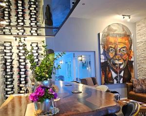 a room with a table and a painting of a man at Fleur du Soleil Luxury Guesthouse in Franschhoek