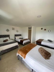 a bedroom with three beds in a room at CASONA HOTEL LA DIVISA in Santa Rosa de Cabal