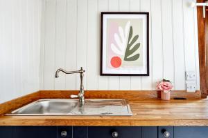 a sink in a kitchen with a picture on the wall at Extraordinary Huts Ltd in Rye