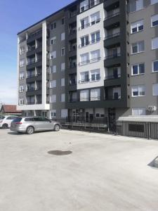 ein Parkplatz vor einem großen Apartmenthaus in der Unterkunft Apartman 49 in Subotica