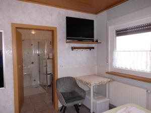 a bathroom with a shower and a television on the wall at Ferienwohnung Schöne Aussicht in Diemelsee