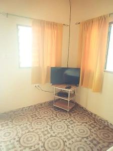 a room with a television and a table on a floor at The Aladin House in Tujering