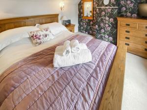 a bedroom with a bed with two towels on it at Folly Cottage in Avening