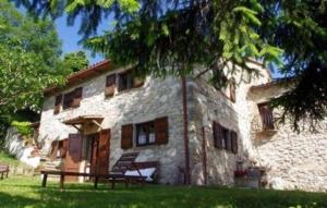 una casa de piedra con un banco delante en Tolles Ferienhaus in Urbino mit Grill, Garten und Terrasse, en Urbino