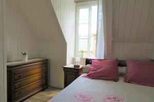 una camera da letto con un letto con cuscini rosa e una finestra di Maison typique de pêcheur, rénovée avec wifi à PERROS-GUIREC - Réf 867 a Perros-Guirec