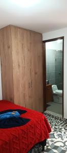 1 Schlafzimmer mit einem roten Bett und einem Badezimmer in der Unterkunft Lindo Apartamento 2 in Jardin