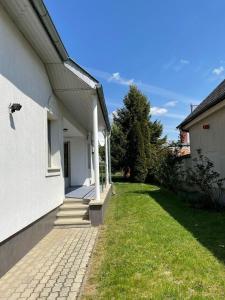 フェルテードにあるFreistehendes Ferienhaus mit Swimmingpool, Kamin, Internet, unweit Neusiedlerseeの芝生の庭のある白い家の横からの眺め