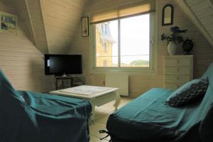 salon z telewizorem, kanapą i stołem w obiekcie Appartement 5 pers sur la plage à Ploumanac'h, VUE MER à PERROS-GUIREC - Réf 897 w mieście Perros-Guirec
