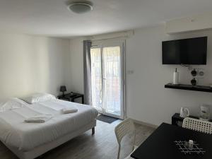 a white bedroom with a bed and a tv on the wall at Au coeur des Chateaux de la Loire in Fondettes