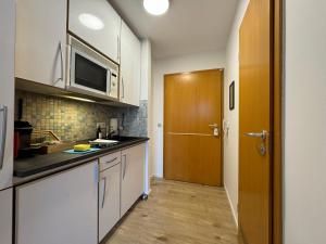 cocina con armarios blancos y puerta de madera en Gemütliches Apartment für 2 Personen nahe RaumFabrik - Durlach by Rabe, en Karlsruhe