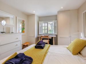 a bedroom with a bed with a yellow blanket on it at Pensway in Burpham +10 photos