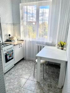 een keuken met een witte tafel en een fornuis bij 1 комн. кв. 5 микрорайон in Aqtöbe