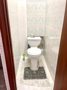 een badkamer met een toilet in een betegelde kamer bij 1 комн. кв. 5 микрорайон in Aqtöbe