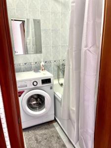 een badkamer met een wasmachine en een spiegel bij 1 комн. кв. 5 микрорайон in Aqtöbe